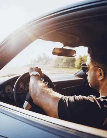 Driver in a car with window tint on a sunny day